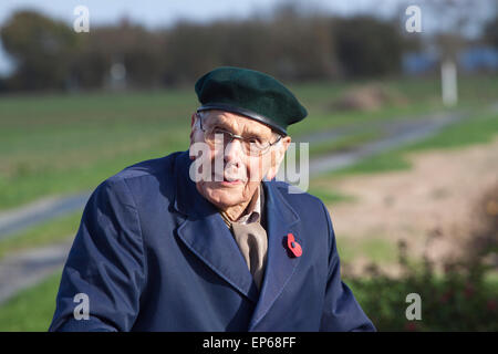 Un anziano/senior uomo che indossa un Giorno del Ricordo papavero, berretto e un impermeabile blu Foto Stock