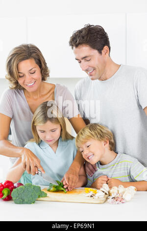 Padre e figlio guardando la madre e la figlia per affettare verdura Foto Stock