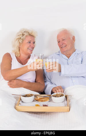 Vecchia coppia tostare a colazione con succo d'arancia Foto Stock