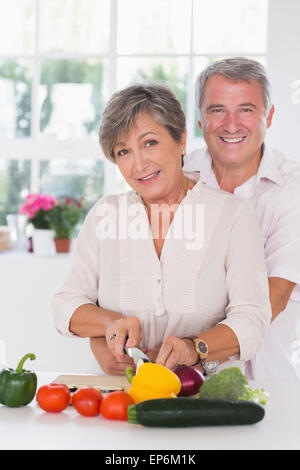 Ritratto di una donna il taglio di verdure con suo marito dietro di lei Foto Stock