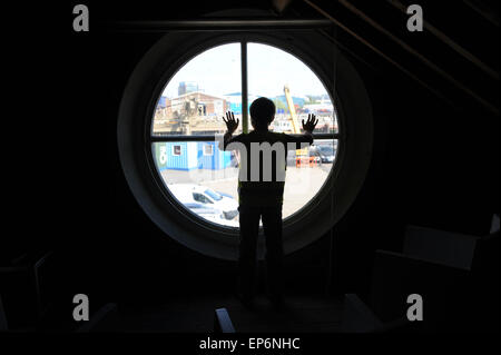 10 anno vecchio ragazzo inglese guardando fuori della finestra del faro in Boa Trinity Wharf faro. Foto Stock
