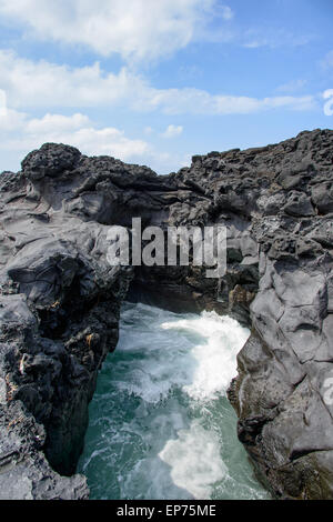 Paesaggio con spruzzi di acqua da acqua di mare ha colpito attraverso il tunnel tra le rocce presso la costa vicino a Olle sentiero percorso 16 in Jeju Foto Stock