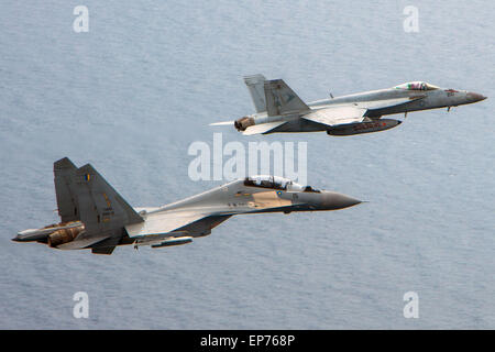 Un U.S. Navy F/A-18C Hornet fighter aircraft vola in formazione con un russo fatto Royal Malaysian Air Force SU-30MKM Flanker H fighter durante un esercizio congiunto con la portaerei USS Carl Vinson 10 maggio 2015 nel Mare della Cina del Sud. Foto Stock