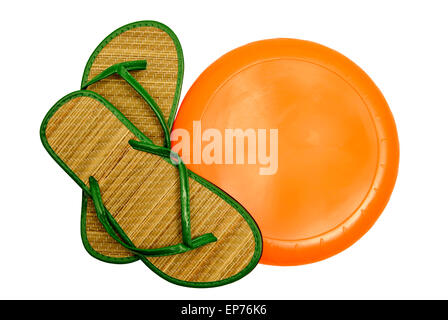 Divertimento al sole con arancio brillante Blank Frisbee e colorato sandali verdi su sfondo bianco. Inquadratura orizzontale Foto Stock