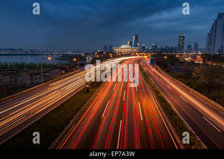 Il traffico sfuma lungo la parkways di Seoul, con l'Assemblea nazionale illuminato nella distanza. Foto Stock