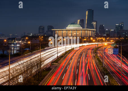 Il traffico sfuma lungo la parkways di Seoul, con l'Assemblea nazionale illuminato nella distanza. Foto Stock