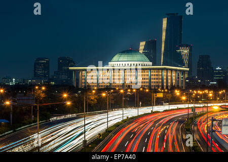 Il traffico sfuma lungo la parkways di Seoul, con l'Assemblea nazionale illuminato nella distanza. Foto Stock
