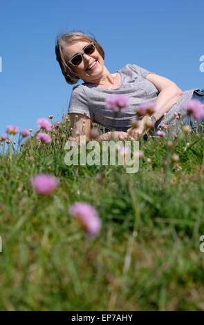 Senior donna posa sull'erba Foto Stock