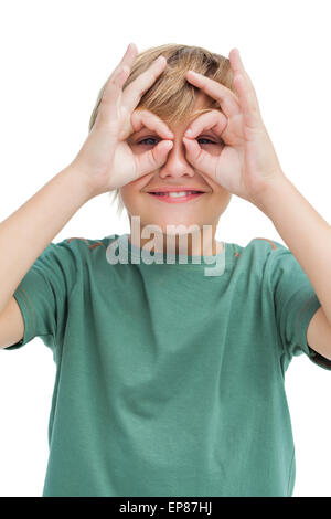 Felice piccolo ragazzo rendendo gli occhiali con le sue dita Foto Stock