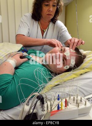 Leipzig, Germania. 24 apr, 2015. Sabine infermiere pone gli elettrodi sul paziente con il sonno di un disturbo del sonno in laboratorio del sonno di Robert Koch clinica di Leipzig, Germania, 24 aprile 2015. In otto camere singole, i pazienti vengono agganciate e videoregistrate per monitorare le onde cerebrali, il respiro, il ritmo cardiaco e tutti i movimenti durante il sonno. Foto: Waltraud Grubitzsch/dpa/Alamy Live News Foto Stock