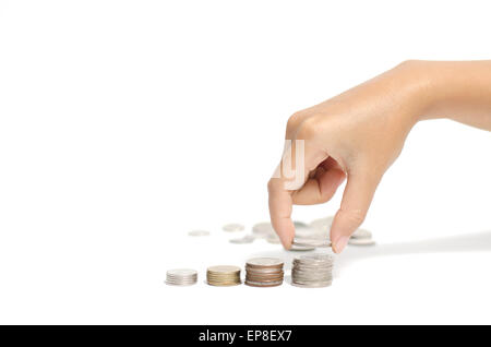 Donna mettendo mano pila di monete su sfondo bianco Foto Stock