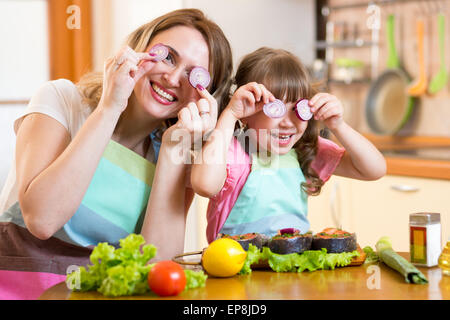 Madre e figlia gioca con verdure in cucina, cibo sano Foto Stock