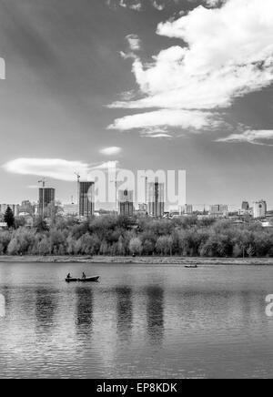 Unica barca a remi su un lago con alto edificio di appartamenti in bianco e nero Foto Stock