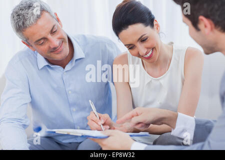 Donna sorridente firmare un contratto con la sua partnership sul divano Foto Stock