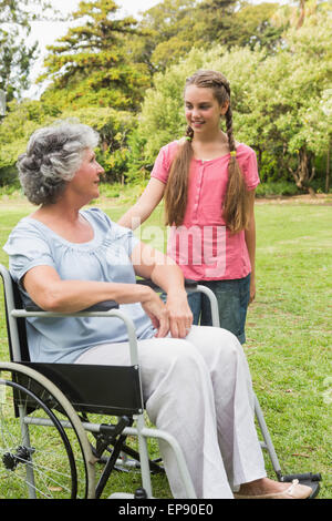 Nipote sorridente con la nonna in sedia a rotelle Foto Stock