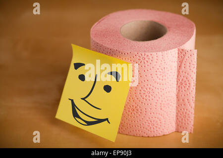 Post-it con faccina sorridente incollata su una carta igienica Foto Stock