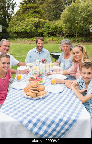 Allegro famiglia estesa avente la cena all'aperto al Tavolo picnic Foto Stock