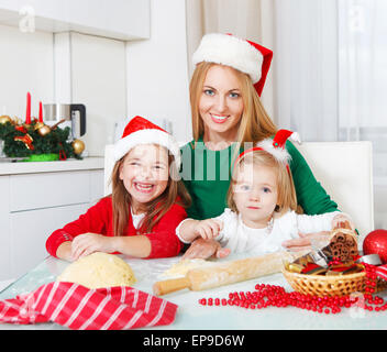 Due ragazze con la madre la cottura biscotti di Natale in cucina Foto Stock