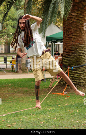 Uomo con dreadlocks e tatuaggi in equilibrio su una fune Foto Stock