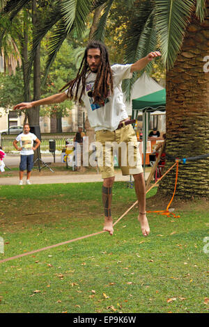 Uomo con dreadlocks e tatuaggi in equilibrio su una fune Foto Stock