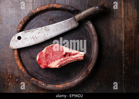 Carne cruda Ribeye entrecote e carne cleaver su sfondo scuro Foto Stock