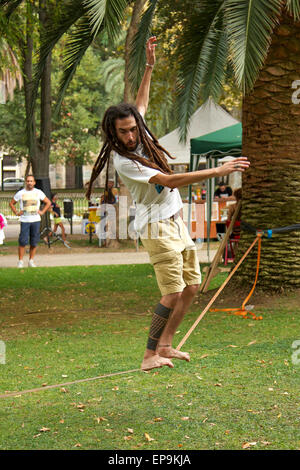 Uomo con dreadlocks e tatuaggi in equilibrio su una fune Foto Stock