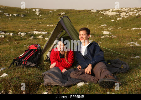Junges Paar schaut beim Zelten in den Bergen Sonnenuntergang dem entgegen Foto Stock