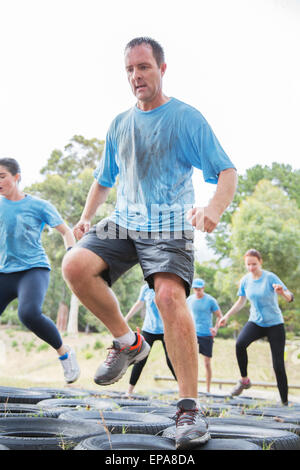 L'uomo jumping pneumatico boot camp ostacolo corso Foto Stock