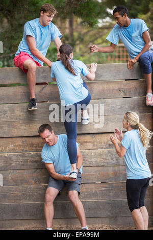 Aiutare la donna parete boot camp ostacolo corso Foto Stock