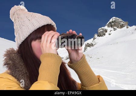 Junge Frau schaut in den Bergen durch ein Fernglas Foto Stock