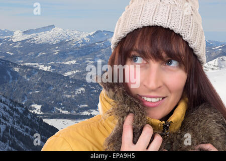 Junge Frau schaut in den Bergen im Winter nach oben Foto Stock
