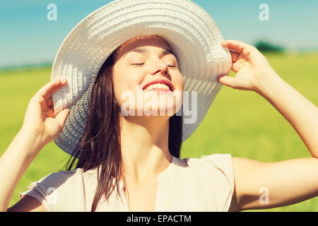 Sorridente giovane donna nel cappello di paglia all'aperto Foto Stock