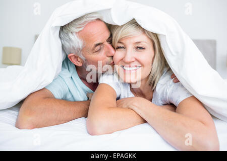 Primo piano di uomo maturo kissing womans guancia a letto Foto Stock