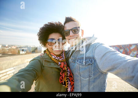 Felice coppia adolescente tenendo selfie sulla strada di città Foto Stock