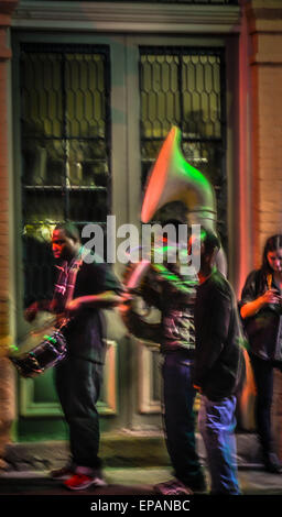 A tarda notte musicisti di strada intrattenere su un oscurato Bourbon Street nel Quartiere Francese sotto la pioggia a New Orleans, LA Foto Stock