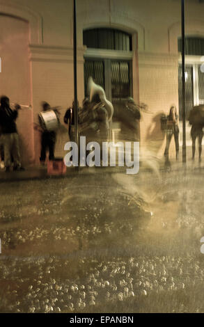 A tarda notte musicisti di strada intrattenere su un oscurato Bourbon Street nel Quartiere Francese sotto la pioggia a New Orleans, LA Foto Stock