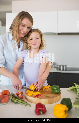 La madre ad assistere la figlia a tritare il capsicum Foto Stock