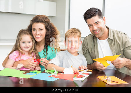 Sorridente famiglia facendo arti e mestieri assieme al tavolo Foto Stock