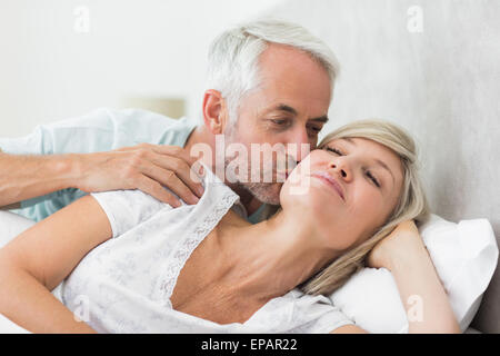 Uomo maturo kissing womans guancia a letto Foto Stock