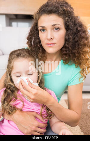 Preoccupato madre aiutare la sua piccola figlia soffiare il naso Foto Stock