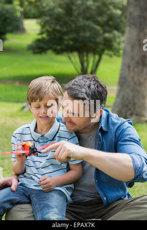 Ragazzo con aeroplano giocattolo seduto sul padre di giro in posizione di parcheggio Foto Stock