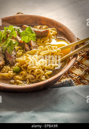 Carni bovine ramen servito in stile asiatico. Uovo crudo cuochi in fumante brodo salato Foto Stock