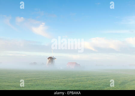 Splendido mulino a vento olandese nella nebbia mattutina, Paesi Bassi Foto Stock