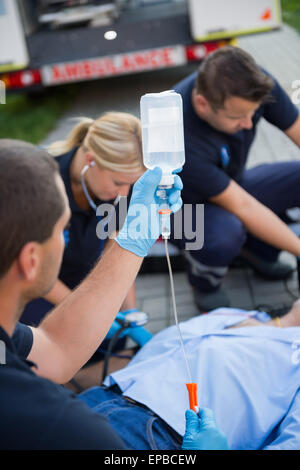 Paramedic team preparazione sgocciolare per Paziente ferito Foto Stock