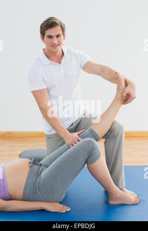 Personal trainer gravide di sollevamento gamba client Foto Stock
