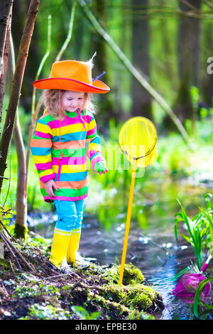 Bambino che gioca all'esterno. Preschooler kid la cattura di rana con colorati net. Bambina con attività di pesca in una foresta fiume in estate. Foto Stock