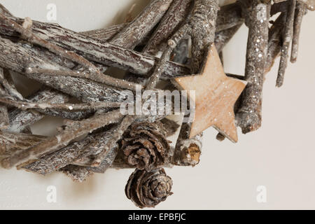 Rami intrecciati tra loro decorazione di Natale con la stella di legno e un po' di pigne Foto Stock