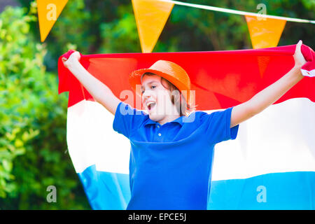 Ragazzo olandese, appassionato di calcio, il tifo e il supporto di squadra di calcio dei Paesi Bassi nel corso del campionato, celebrando la vittoria sportiva Foto Stock