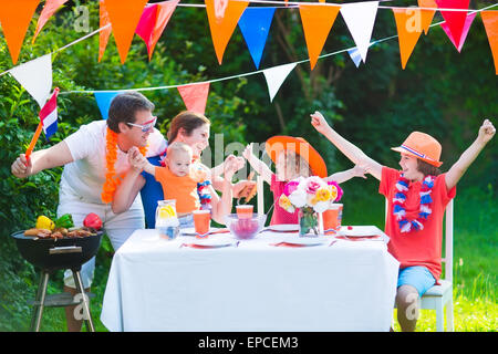 Felice grande famiglia olandese con i bambini per celebrare una festività nazionale o lo sport vittoria avente il divertimento a un grill party in giardino Foto Stock