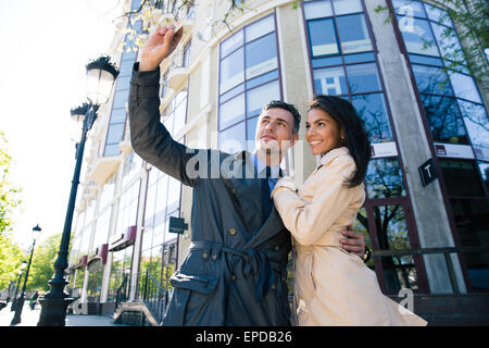 Coppia sorridente rendendo selfie foto sullo smartphone sulla strada di città Foto Stock